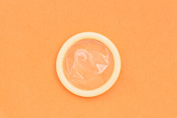 Condom on orange background. Copy space