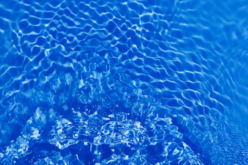 Defocus blurred transparent blue colored clear calm water surface texture with splashes and bubbles. Trendy abstract nature background. Water waves in sunlight with copy space. Blue watercolor shining