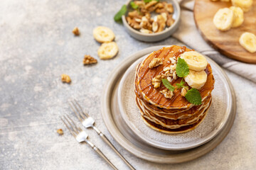 Celebrating Pancake day, american homemade breakfast. Banana gluten free pancakes with nuts and caramel on stone tabletop.