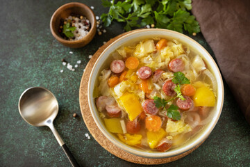 Traditional Zelnacka cabbage soup with sausages and vegetables in a bowl on a stone tabletop. Czech cuisine. Copy space.