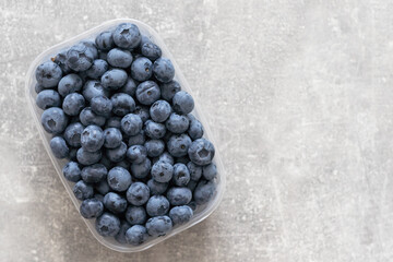 Freshly blueberry in a plastic box packed on a white background. space for text.