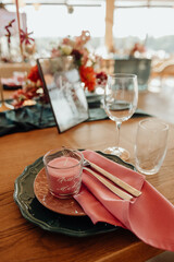 Table setting with cutlery and glass. A plate with a gold ornament on which lie a silver fork and knife.
