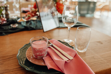 Table setting with cutlery and glass. A plate with a gold ornament on which lie a silver fork and knife.