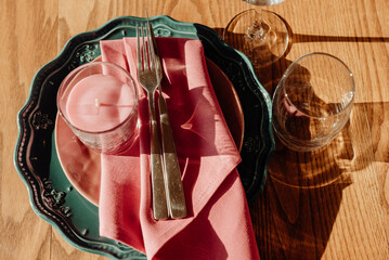 Table setting with cutlery and glass close-up. A green plate with a gold ornament on which lie a...