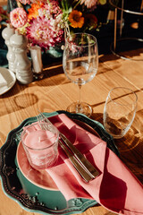 Table setting with cutlery and glass close-up. A green plate with a gold ornament on which lie a silver fork and knife.