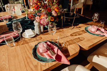 Decoration and table setting in the restaurant for the holiday. Professional floristry with fresh flowers. Decoration with candles and green glass and fabric details