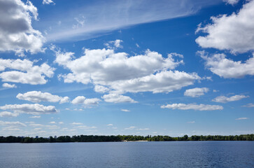 Beautiful river landscape. Lake surface on a sunny perfect day. The surface of the water against the background of trees and a blue sky. Blurred image, selective focus