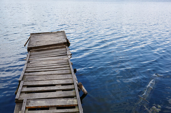 wooden pier on the river bank. Ripple on the water surface. Blurred image, selective focus