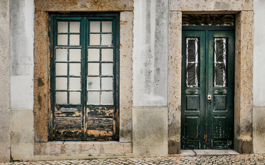 Chipped facade with old green wooden door and window