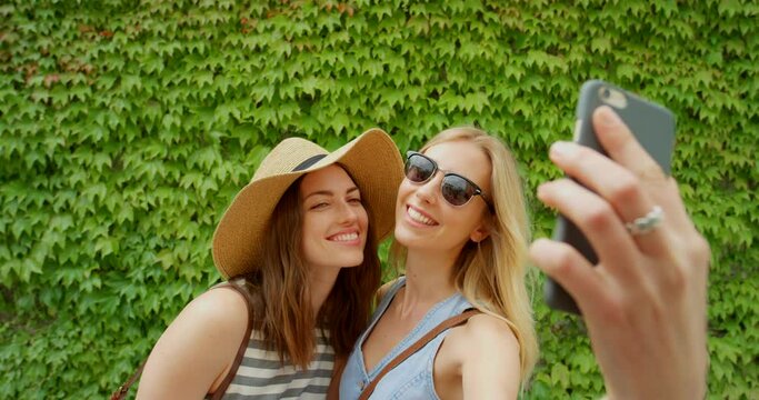Selfie, green and women or people on travel holiday for social media post, blog update and smartphone memory. Gen z, youth and influencer friends in phone portrait photography on ivy garden backdrop
