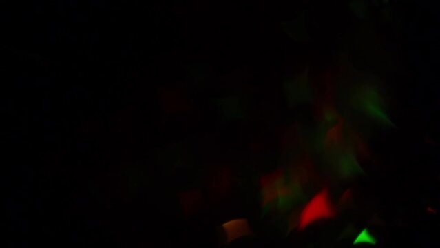 Smooth Diagonal Overflow of Christmas Stars Bokeh. Abstract festive moving background. Red and green quadrangular bokeh stars on a dark background.