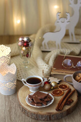 Cup of tea or coffee, various sweets and spices, Christmas decorations, comfy blanket, books and glasses. Selective focus.