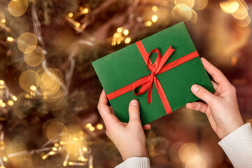 Christmas Gift Certificate or New Year Gift Envelope in Girls hands on Christmas Lights Background....
