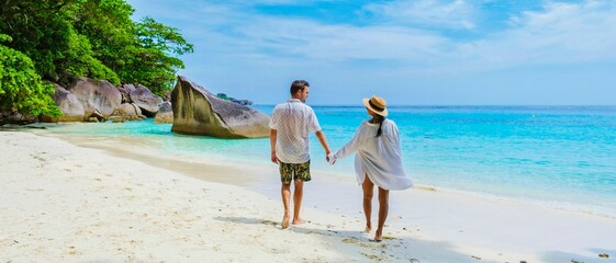 Caucasian men and Thai Asian women on the tropical white beach with turqouse colored ocean of Similan Islands Thailand.