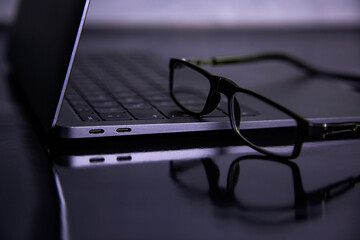 glasses on laptop on black background 