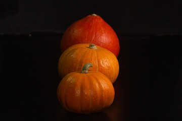 Yellow-orange pumpkins on a black background the concept of Halloween and the autumn harvest of pumpkin close-up copyspace from above