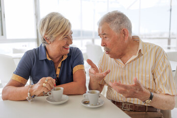 coppia di anziani scherza felice seduti al bar sorseggiando un caffè 