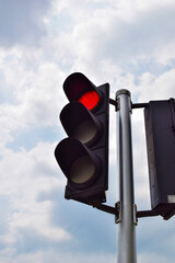 Red traffic light on sky background.