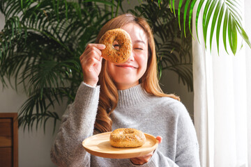 Portrait image of a young woman in sweater holding and playing with a piece of bagel