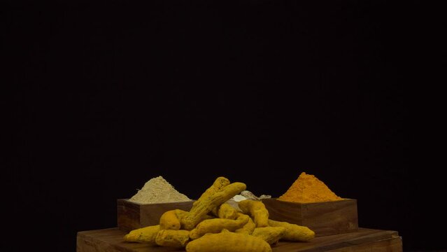 Collection of Indian spices in wooden containers - common Indian spices  Indian herbs. An assortment of natural spices like Haldi powder  Haldi sticks  dried powdered ginger  and dried ginger roots...