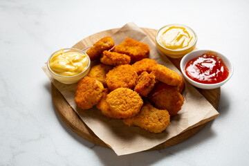 Close up of crisp nuggets on wooden fast food and three dips