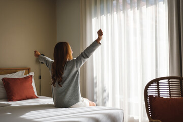 Rear view image of a woman do stretching after waking up in bedroom