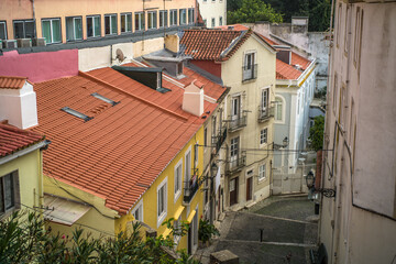 Fototapeta na wymiar historic buildings of the old town of lisbon. Old colorful buildings, narrow streets, historic churches. Tiled roofs. View from the top of the viewpoint on the tenement houses and monuments. Clouds