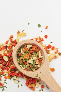 Top view of mixed pieces of dried vegetables  in wooden spoon with copy space.  Dehydrated vegetables mix for cooking on white background