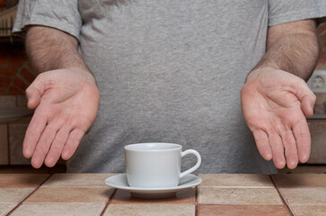 Male hands have just placed a coffee cup on a tiled kitchen table