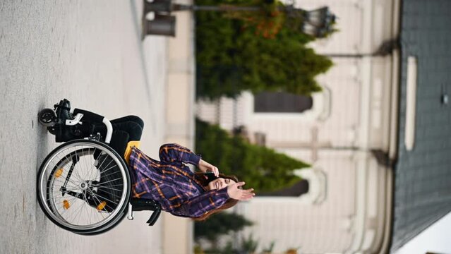 Woman with disability who uses a wheelchair using a smartphone in a city