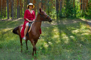 Woman in red dress rides a horse in early spring
