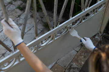 Hand wearing gloves and painting with a paint brush.