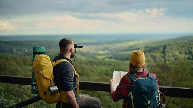 Couple of hikers looking at binoculars and map while out in the nature