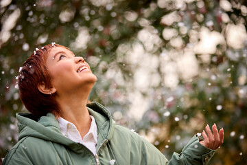 Smiling Young Woman Wearing Coat Standing Outside In Snowy Winter Countryside Catching Snowflakes