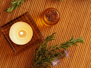 Obraz na płótnie Canvas Candle, essential oil, and rosemary. Flat lay on a reed napkin