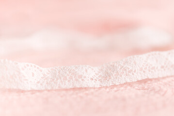 Delicate pink knitted background texture, close-up. Decor with openwork white ribbon.