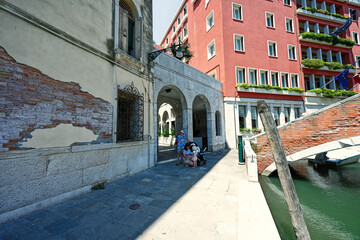 Mother with children stand near canal in Venice, Italy.