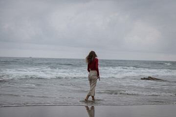 Young caucasian woman on the  Ocean Beach. Girl outdoor portrait on a sea background, brunette in red shirt, naturalness