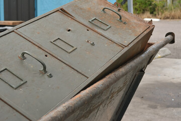 old rusty locked filing cabinet in the dumpster
