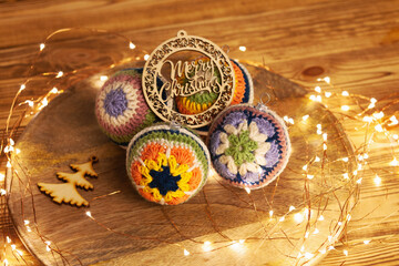 crocheted decorations for the Christmas tree. Bright balls with different crochet pattern of colored lace.  Wooden background and led lights