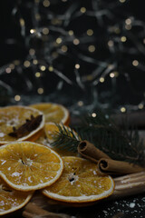 Obraz na płótnie Canvas dried oranges cones cinnamon fir branches and star anise beautifully laid out on wooden natural sticks christmas decoration on a dark background with snow and garlands. for cards calendar labels signa