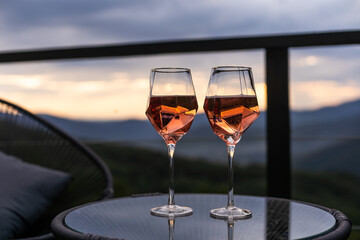 Two glasses of wine standing with a beautiful scenic mountain view. Mountain resort, enjoy moment
