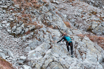 Young girl climbs the rocks on the mountain