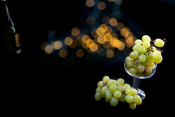 Champagne glass filled with lucky grapes with bokeh lights on black background for New Years Eve