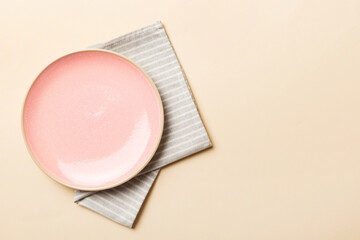 Top view on colored background empty round pink plate on tablecloth for food. Empty dish on napkin with space for your design