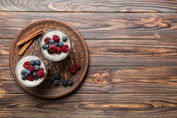 Healthy breakfast or morning with chia seeds vanilla pudding raspberry and blueberry berries on table background, vegetarian food, diet and health concept. Chia pudding with raspberry and blueberry