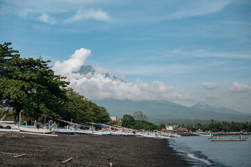 Fototapeta na wymiar Aerial view of Amed beach in Bali, Indonesia. Traditional fishing boats called jukung on the black sand beach and Mount Agung volcano