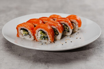 Eight servings of sushi with salmon and cucumber on a white plate. 