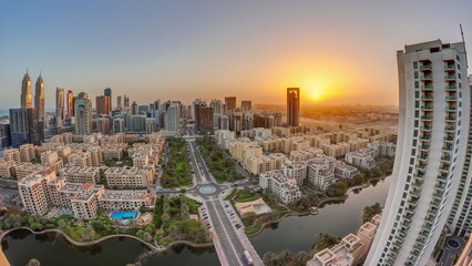 Fototapeta na wymiar Sunrise over skyscrapers in Barsha Heights district and low rise buildings in Greens district aerial timelapse.