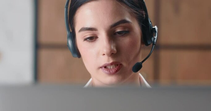 Close-up shot, woman hotline operator in large banking organization advises customers and tells them about the advantages of bank. Millennial woman works in bank office and advises clients on phone.